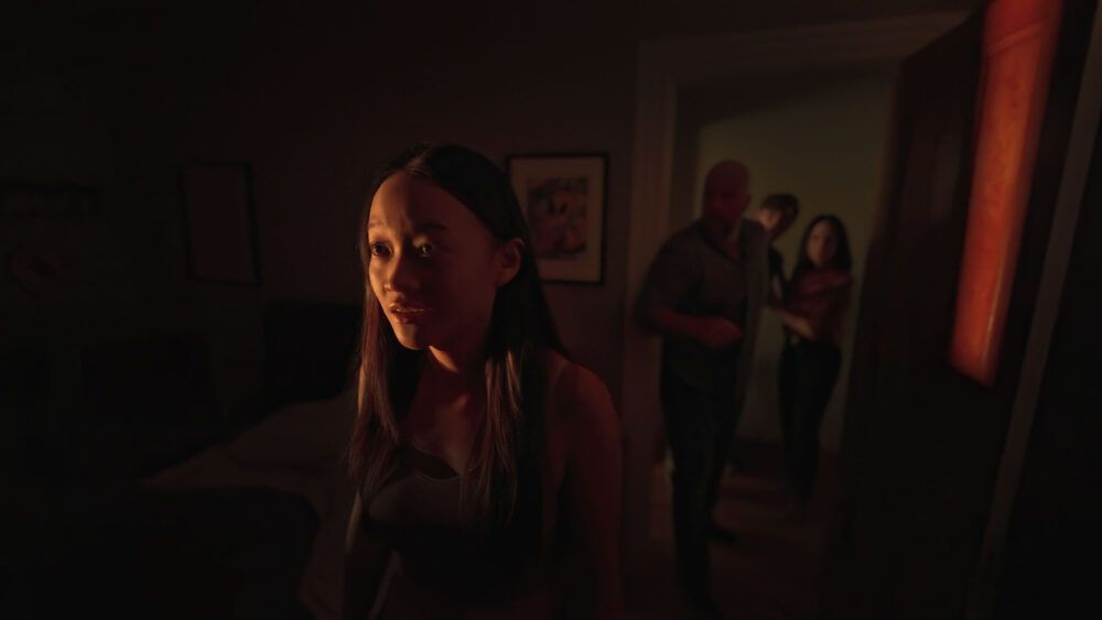 Woman looks concerned with blurred figures in doorway in a scene from "Presence.