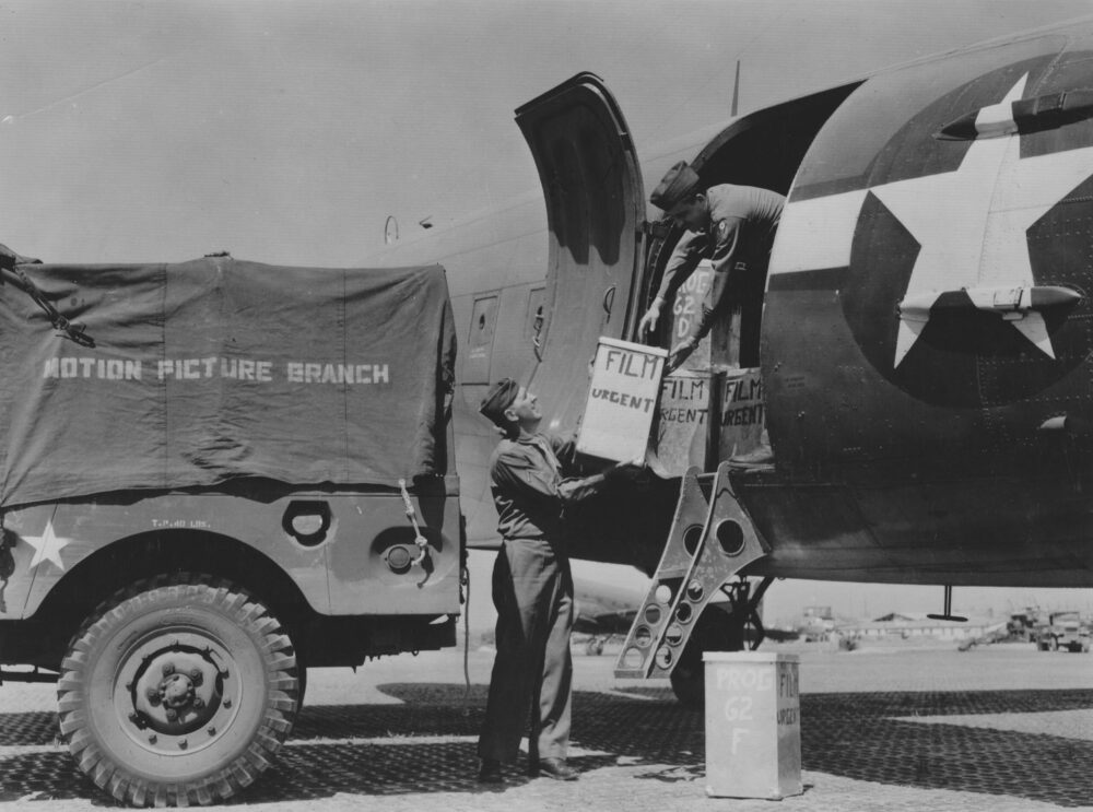 Loading "Urgent" film for "Projections of America" onto a plane from a Motion Picture Branch truck. WWII era.