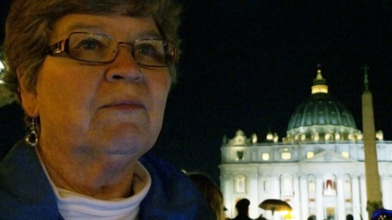 Woman with St. Peter's Basilica in the background at night.
