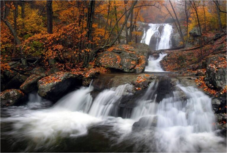 Waterfall cascading over rocks in Rappahannock during autumn with colorful foliage.