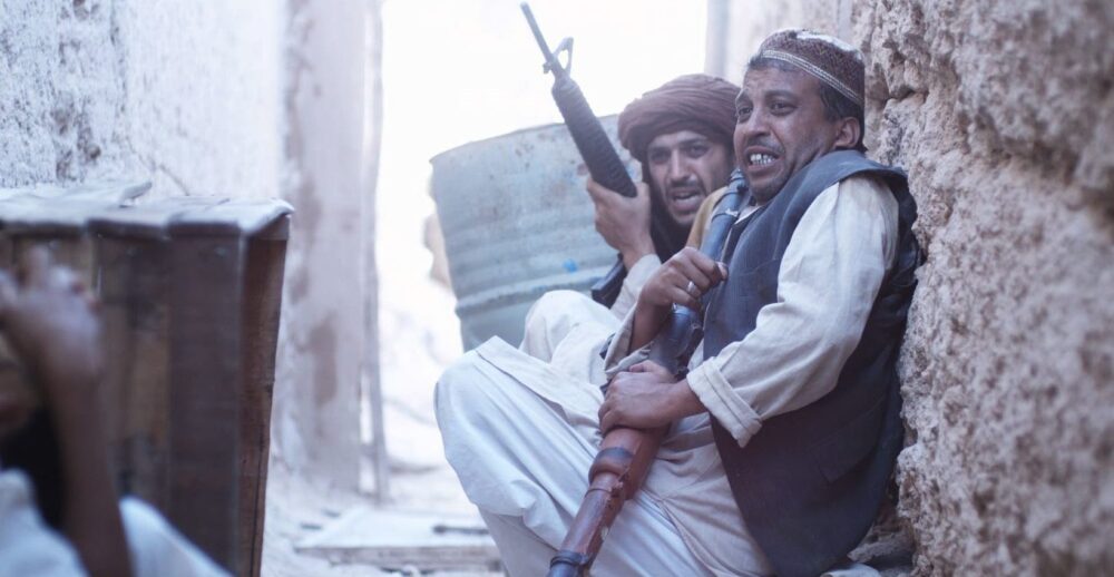 Men with rifles take cover in a Kabul alleyway.