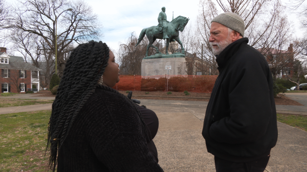 Woman and man discussing statue, possibly related to "Truth Tellers.