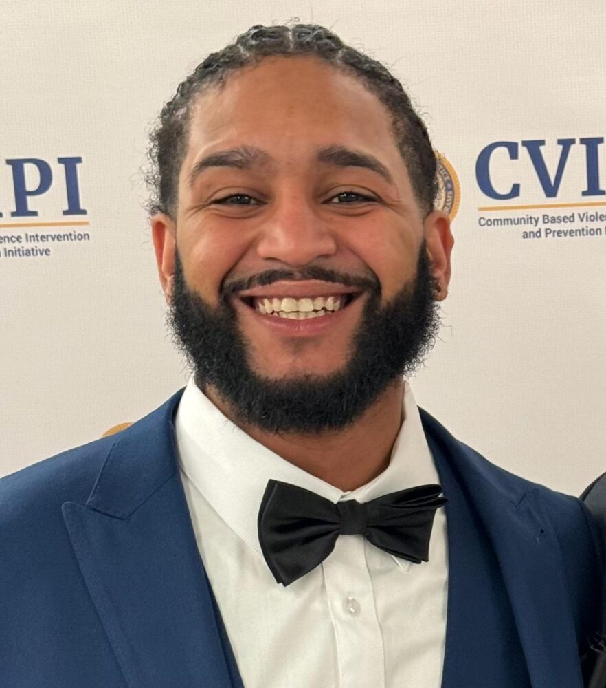 Romeo Gonzalez smiling in a suit and bow tie at an event.