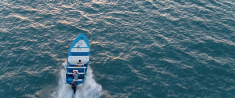 Blue boat with two people sailing on the water in "Sea of Shadows