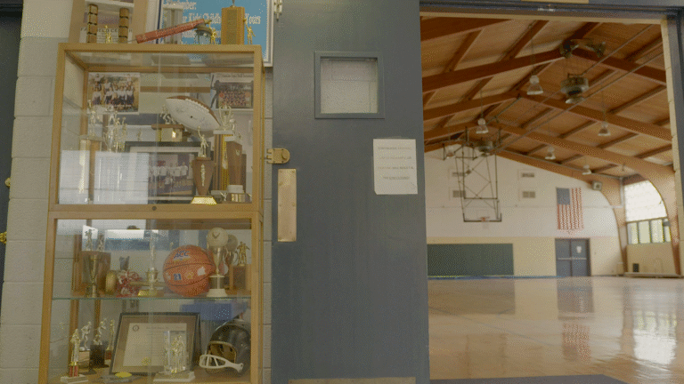 Kinston basketball trophies displayed near the gym entrance with a warning sign.