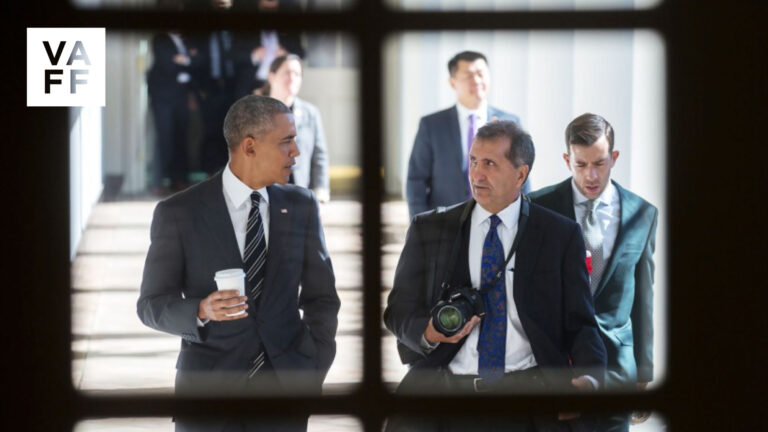 President Obama and Pete Souza walk, Souza holding a camera.