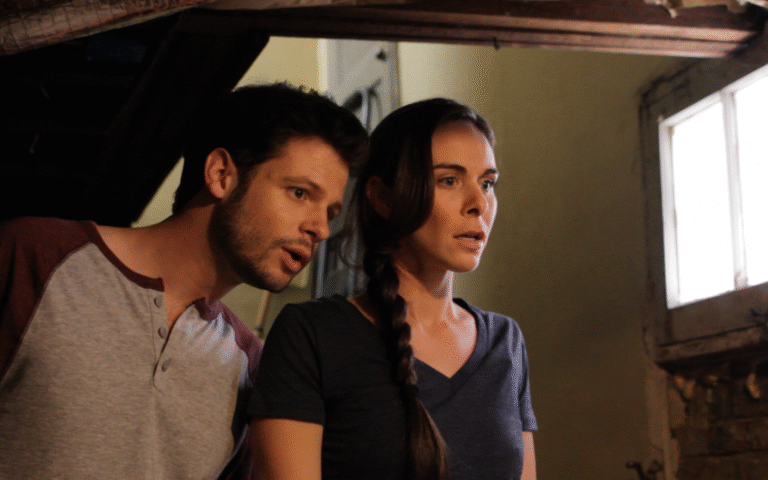Intrigued man and woman looking at something off-camera in a dimly lit room.
