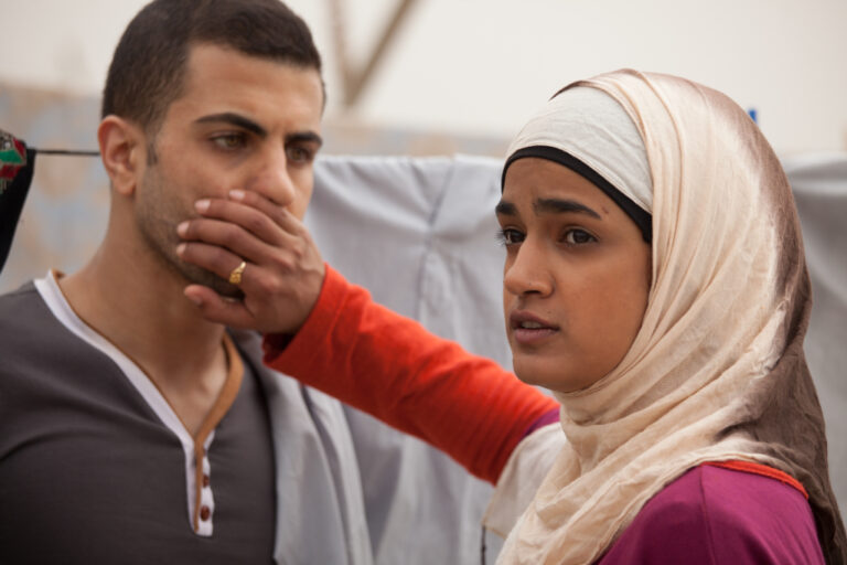 Scene from Sand Storm: Man silencing a woman in a hijab.