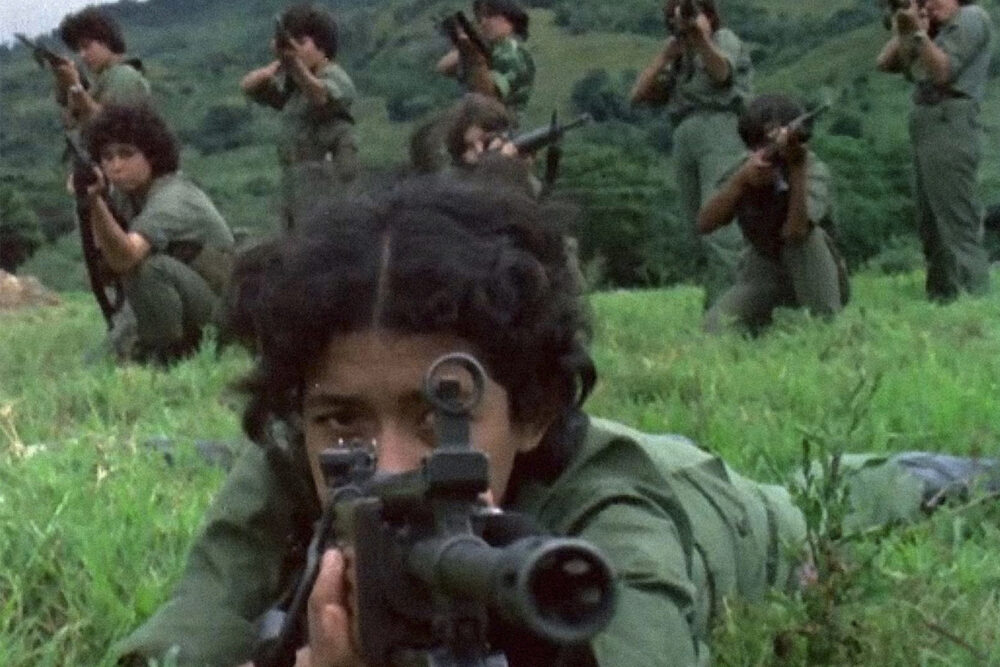 Young Sandinista soldiers aiming rifles in a grassy field. ¡las Sandinistas!