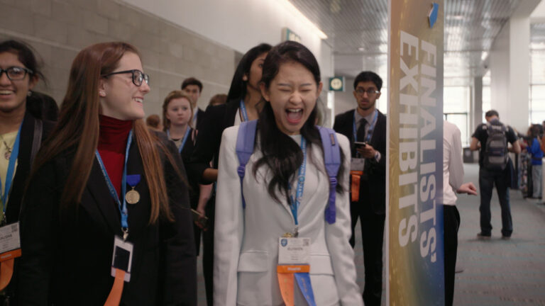 Excited students at a science fair finalists exhibit.