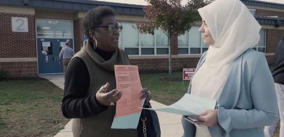 Voters talking outside a polling place with election information.
