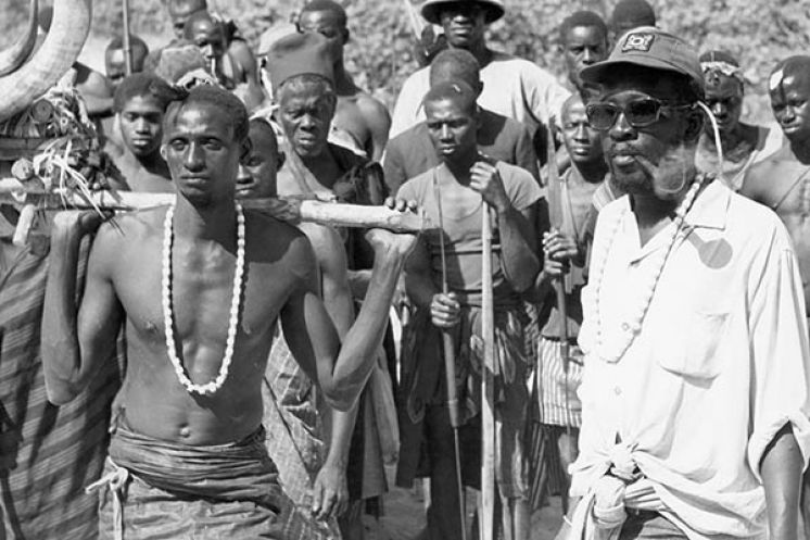 Scene from "Sembene!" film: Men in traditional attire, one carrying horns, another in sunglasses and cap.