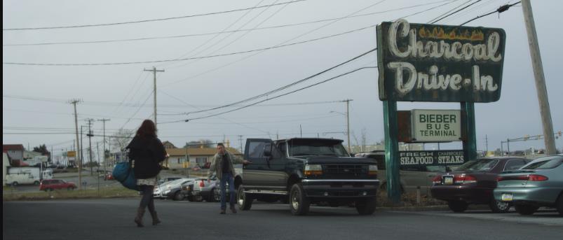 Charcoal Drive-In sign, Bieber Bus Terminal, people walking near a truck.