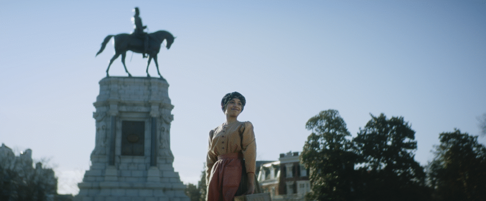 Woman stands near Robert E. Lee statue. Historic monument, civil rights context.