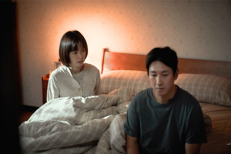 Couple sitting on a bed, looking somber, possibly discussing sleep issues.