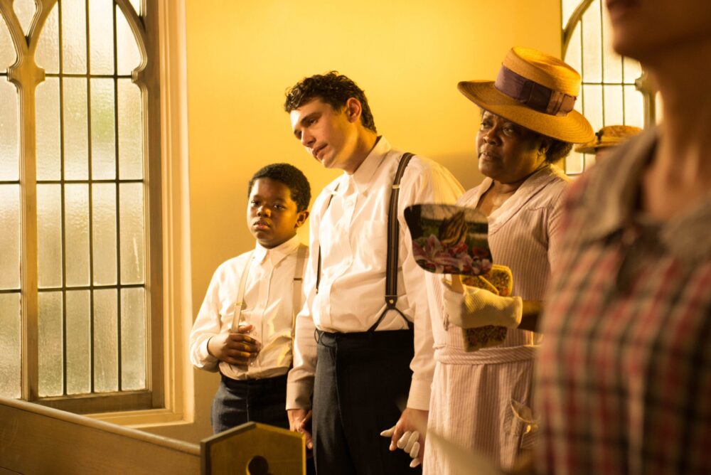 Scene from "The Sound and the Fury" film: a young boy, man, and woman in a church, looking somber.