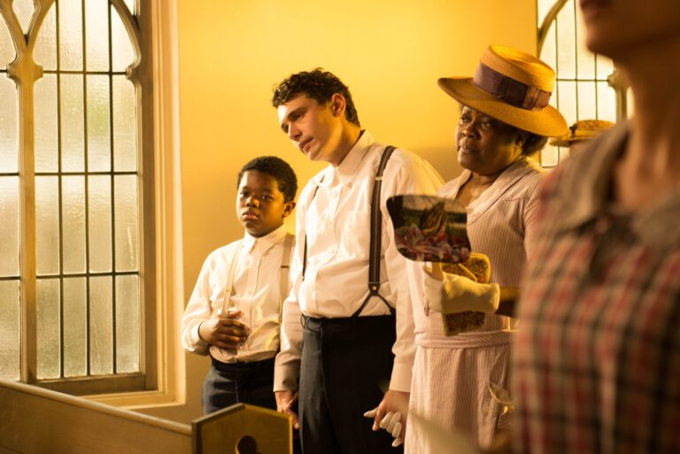 Scene from "The Sound and the Fury" film: a young boy, man, and woman in a church, looking somber.