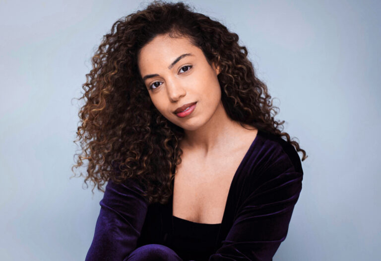 Portrait of Spencer Jamison, a woman with curly hair wearing a velvet top.