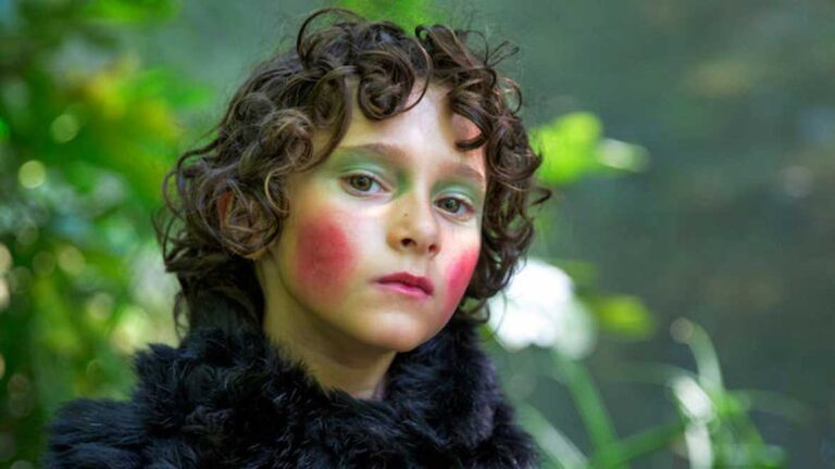 Child with curly hair, green eyeshadow, and red blush, evocative of a 1993 summer aesthetic.