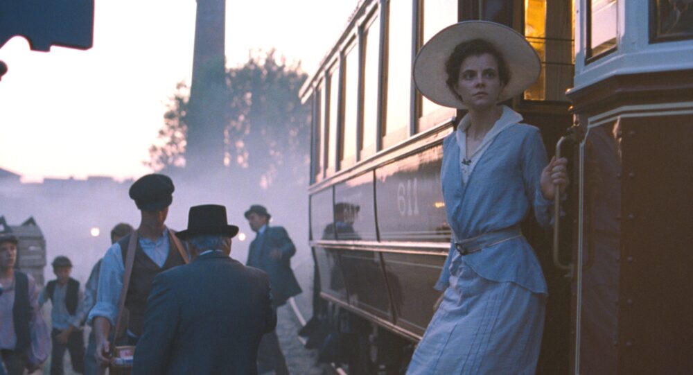 Woman boarding a vintage train at sunset.