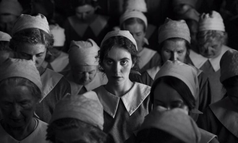 Black and white image of a woman surrounded by other women in uniform caps and collars.