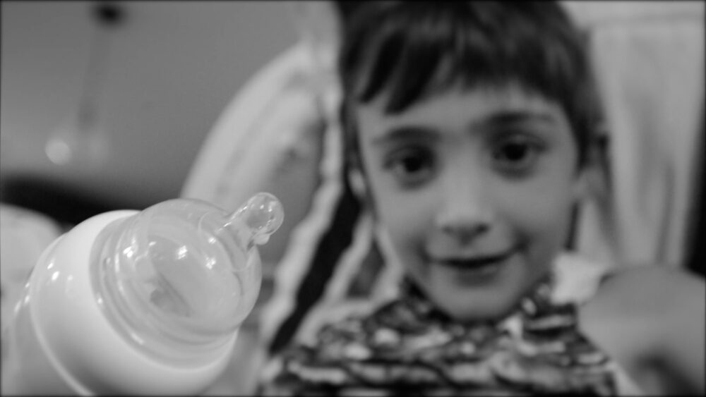 Child looking at a baby bottle, possibly related to short films about self and others.