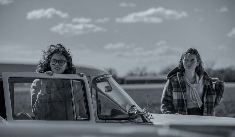 Two young women by a vintage car.
