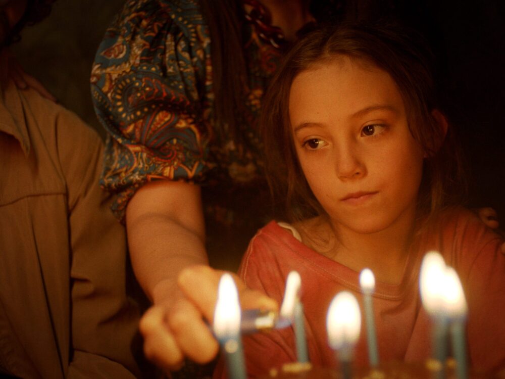 Girl lighting birthday candles, family celebration.