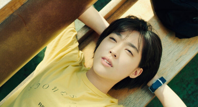 Teenage girl lying on a bench in yellow t-shirt. Text on shirt reads "jones".