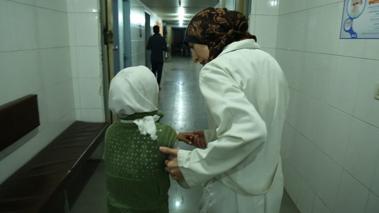 Healthcare worker examines a child in a hospital hallway.