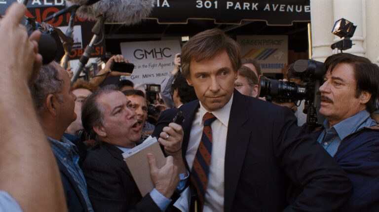 Hugh Jackman as Gary Hart in "The Front Runner" surrounded by media.