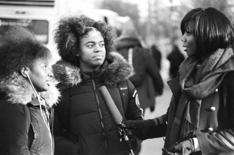 Woman interviewing two people on the street.