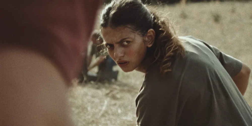 Intense young woman looking back over her shoulder in a field.