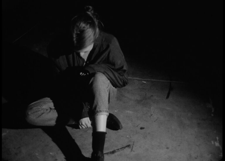 Person hunched over in shadow.