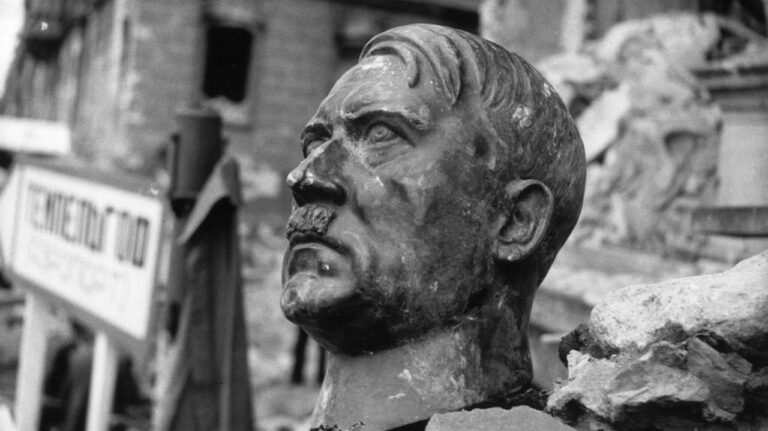 Damaged bust of Hitler amidst rubble, symbolizing the end of his regime.