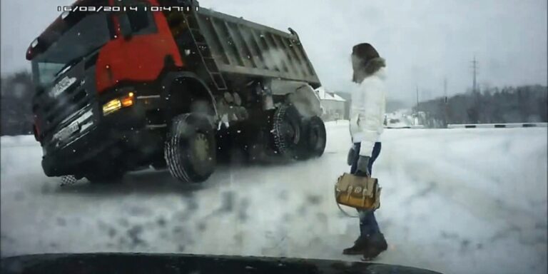 Truck skidding on icy road near pedestrian in "The Road Movie" conditions.