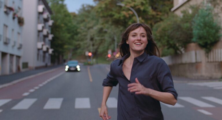 Renate Reinsve running in "The Worst Person in the World," smiling on a city street.