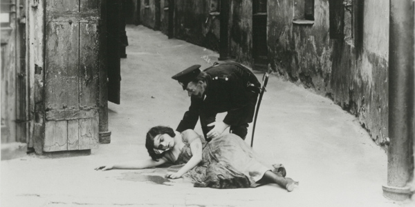 Scene from "The Yellow Ticket" film: a woman lies injured, a police officer attends to her.
