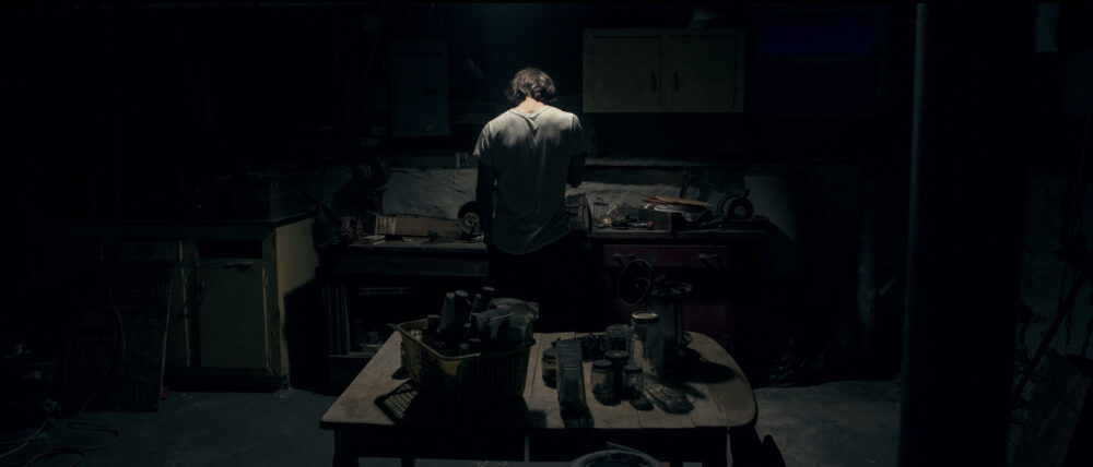 Man in dim workshop, back view.