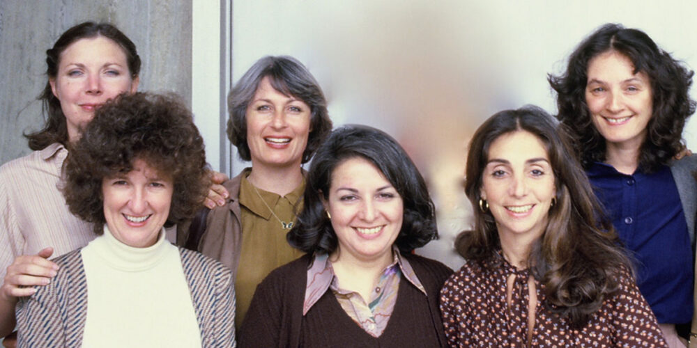 Group portrait of six women posing and smiling for the camera.