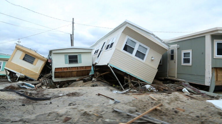 Mobile homes destroyed, likely by hurricane damage. Debris is scattered around the homes.