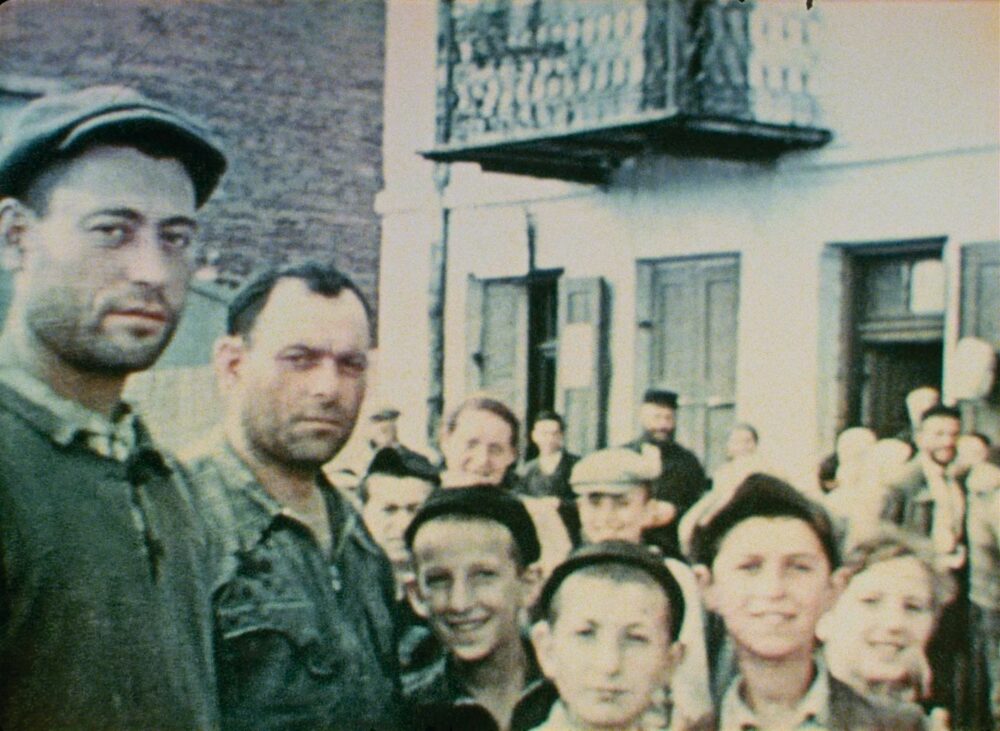 Colorized film still of a crowd, possibly related to "Three Minutes - a Lengthening.