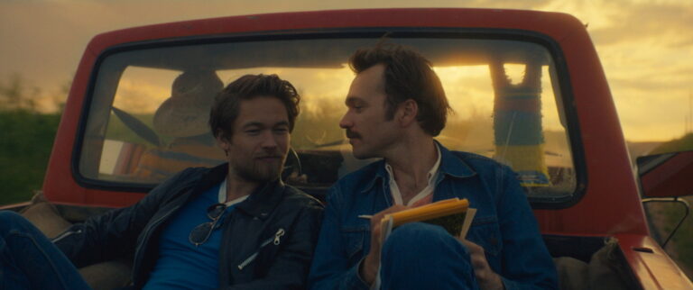 Two men in a red pickup truck.