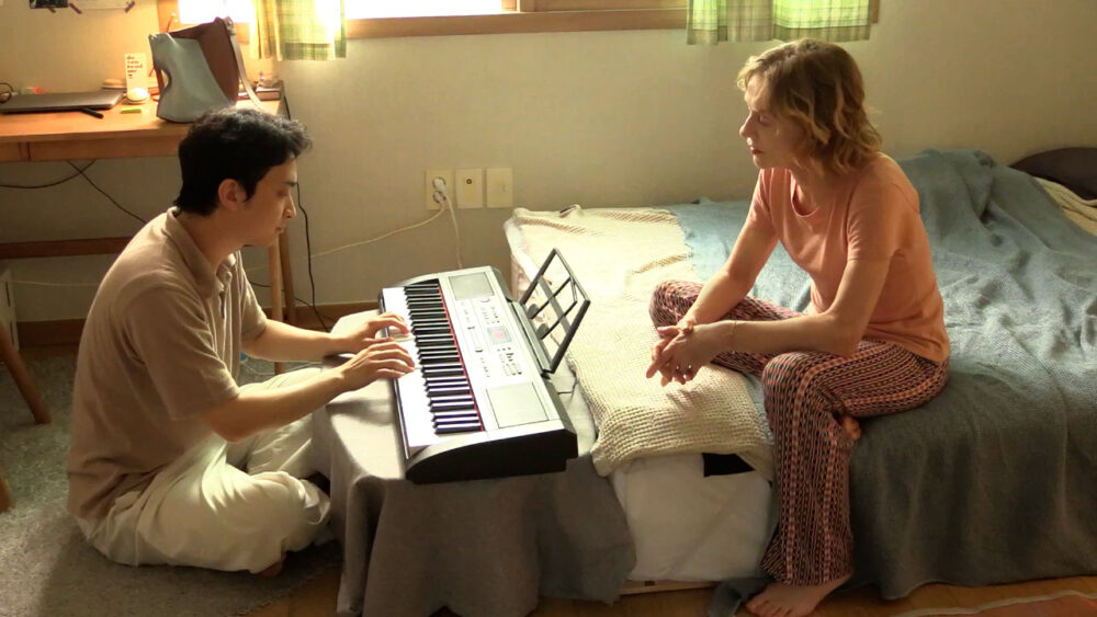 Man plays keyboard for a woman in a bedroom. A traveler's needs.