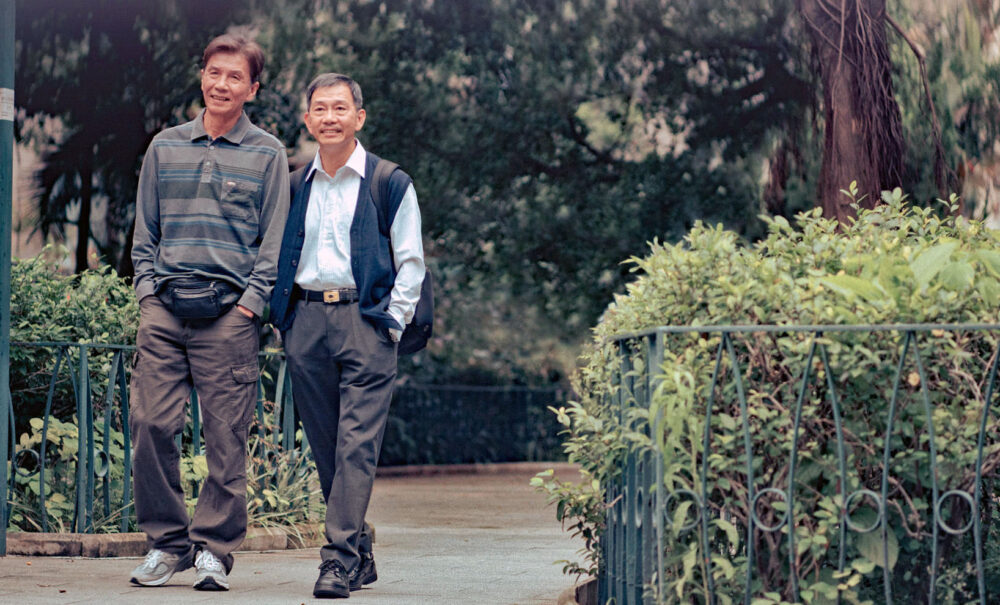 Two older Asian men walking in a park, enjoying twilight's kiss.