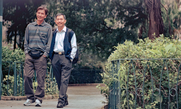 Two older Asian men walking in a park, enjoying twilight's kiss.