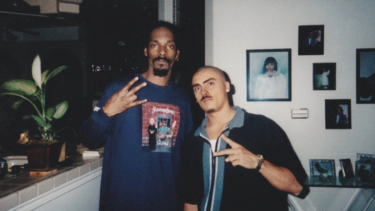 Snoop Dogg and an associate pose, flashing West Coast hand signs.