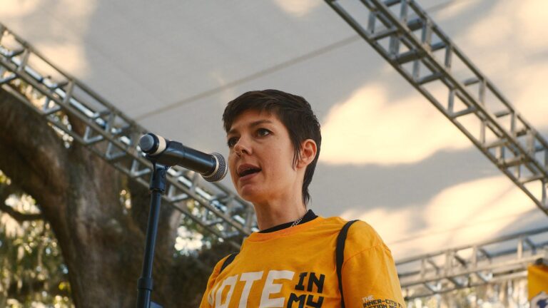 Woman speaking at "Vote in My Mission" rally on stage.