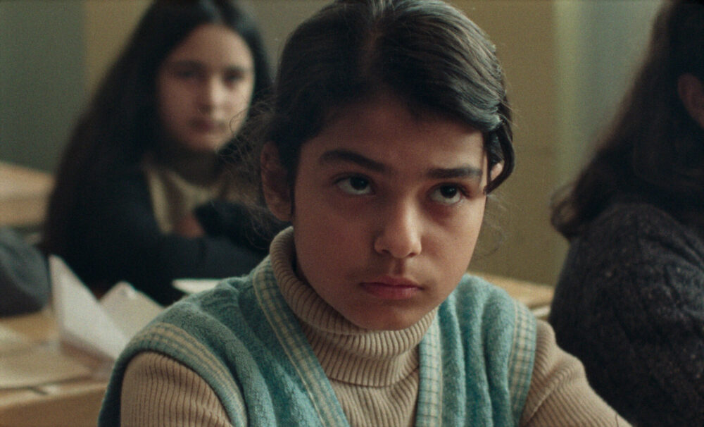 Pensive young girl in classroom. Close-up on child in school setting.