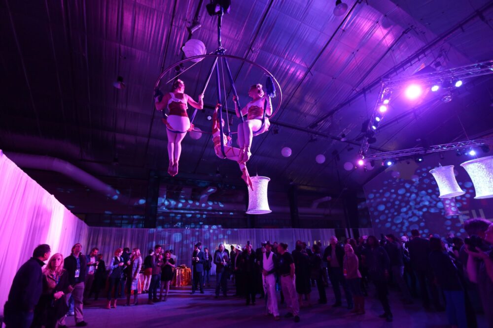 Aerial performers at a late-night wrap party, illuminated by purple lighting.
